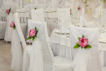 Elegant wedding reception with decorated chairs and floral arrangements in a bright venue