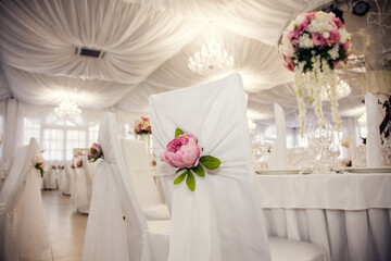 Elegant wedding reception with floral decorations and white table settings in a spacious venue