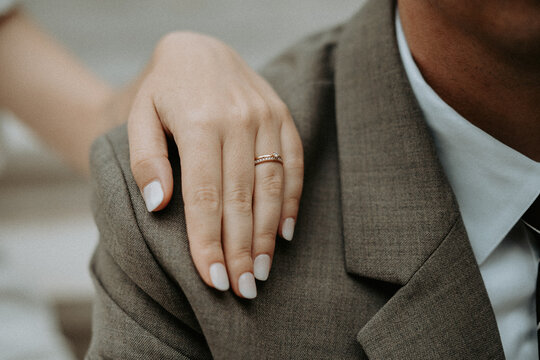 La main de la mari&eacute;e avec son alliance sur l'&eacute;paule du mari&eacute; pendant leur mariage