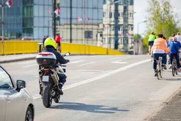 Police officer on motorcycle secures group of cyclists on city road, street, asphalt