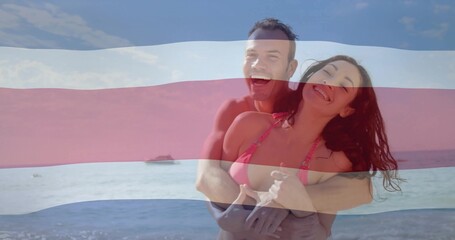 Smiling couple wearing swimwear hugging shoreline of sea, with small boat and pale stripes overlay