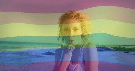 Blowing kisses woman wearing sleeveless lace top on beach, with waves, rocks, pastel stripe overlay