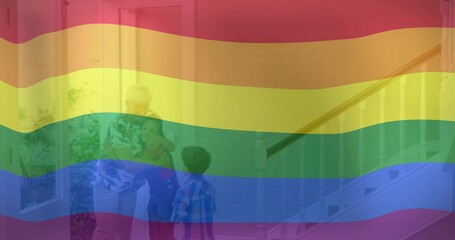Greeting grandparents embracing grandkids in home foyer, with front door, plant, staircase rail