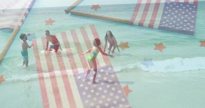 Playing family in swimwear laughing and splashing beach water with American flag and star overlays - Powered by Adobe