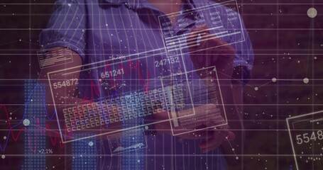 Man wearing blue shirt holding keyboard, swiping data panels at brick wall with holographic charts