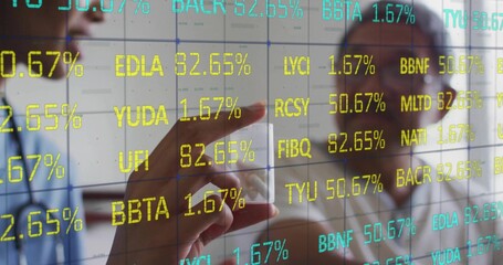 Senior man and woman analyzing financial data on transparent screen in office with pointing finger