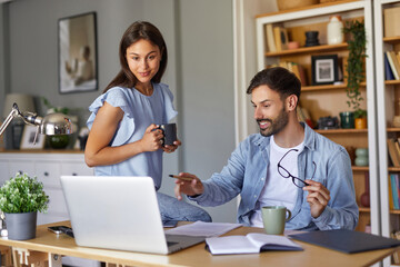 Obraz premium A man and woman are actively engaged in a discussion in their home office, with laptops and notebooks on the table, creating a productive atmosphere during the day.