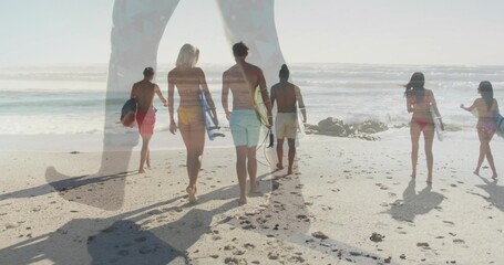 Naklejka premium Walking surfers in swimwear carrying surfboards along beach at low tide with outcrop and footprints
