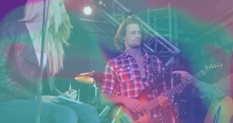 Playing electric guitar, guitarist wearing red shirt on concert stage with drums and trusses