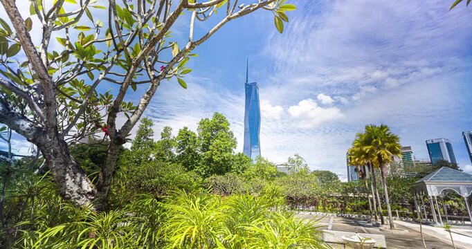 Kuala Lumpur, Malaysia &ndash; 16 September 2025: Merdeka 118 soars behind palm trees and a city park under a bright blue sky, showcasing modern architecture and tropical greenery. time lapse footage