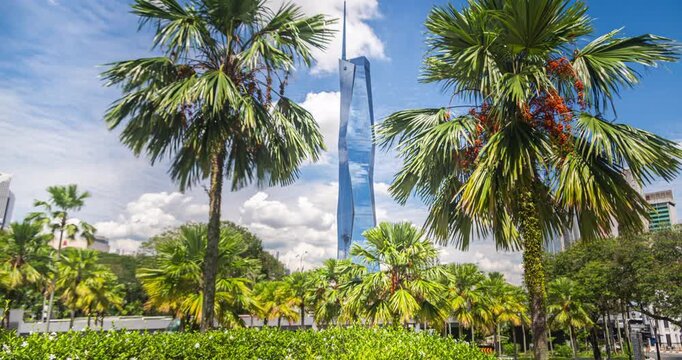 Kuala Lumpur, Malaysia &ndash; 16 September 2025: Merdeka 118 soars behind palm trees and a city park under a bright blue sky, showcasing modern architecture and tropical greenery. time lapse footage