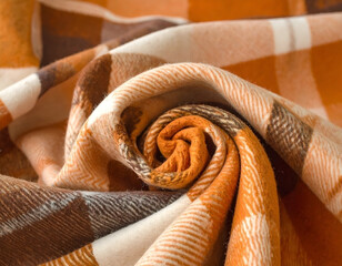 Fototapeta premium A close-up, macro shot of a rolled, soft plaid blanket in warm autumn colors. A cozy, textured background for fall or winter concepts. Generative AI