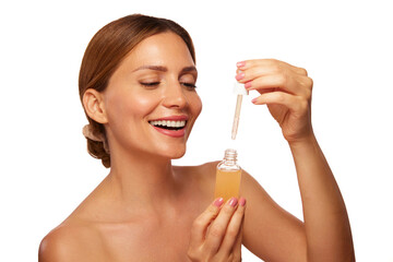 Fototapeta premium A woman smiles as she prepares to apply skin care serum from a dropper bottle. Her glowing skin reflects her enthusiasm for beauty care in a clean, bright environment.