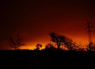 A captivating twilight landscape with silhouetted trees and power lines against a vibrant sky