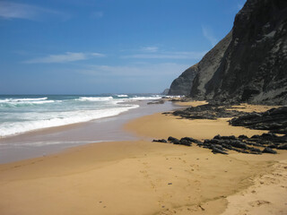 A beautiful sandy beach with a tall cliff in the background
