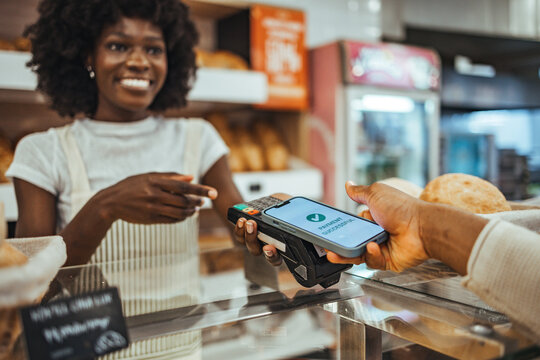 Customer Using Mobile Payment at Artisan Bakery Counter With Friendly Cashier - Powered by Adobe