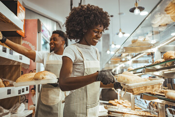 Smiling Bakery Staff Serving Fresh Bread and Pastries Behind the Counter