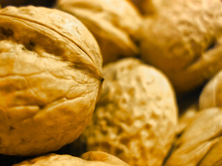 A detailed close up view of a pile of walnuts still in their shells