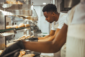 Professional Bakery Staff Preparing Fresh Loaves of Bread in a Commercial Kitchen