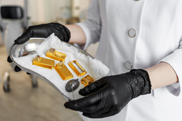 Close-up cosmetologist holding metal tray with golden interchangeable attachments for modern...