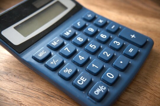 Close-up view of a blue calculator placed on a wooden desk.