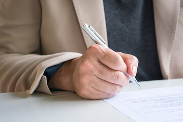 Businessman looking at document about to write or sign on it.