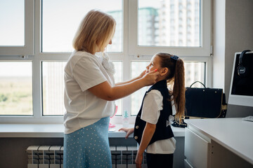 Mother helping daughter get ready in bright modern apartment