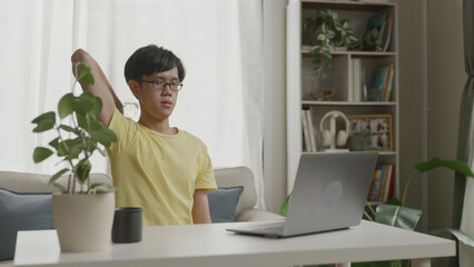 Asian man exercising with dumbbells targeting triceps at home.