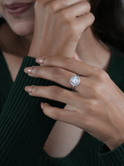 Close-up of a woman wearing a sparkling round diamond halo ring, showcasing luxury jewelry and elegant fashion style.