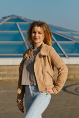 Young woman poses confidently outdoors in a stylish outfit against a modern architectural backdrop