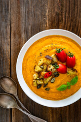 Garnished pumpkin cream soup on wooden table