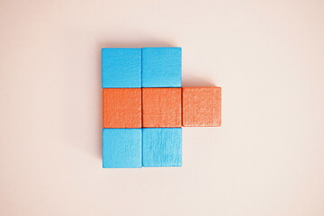 Brightly colored blue and orange wooden blocks arranged to create an abstract geometric design on a...