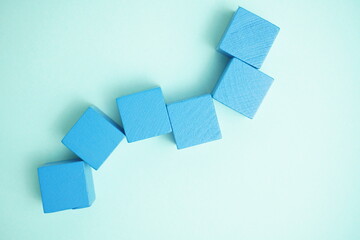 Blue wooden blocks arranged aesthetically on pastel teal background with copy space, symbolizing...