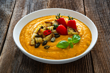 Garnished pumpkin cream soup on wooden table