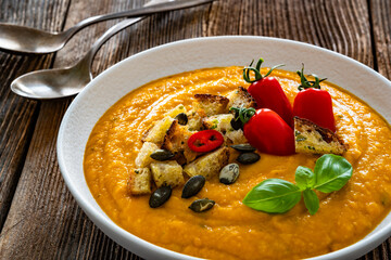 Garnished pumpkin cream soup on wooden table