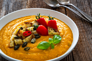 Garnished pumpkin cream soup on wooden table