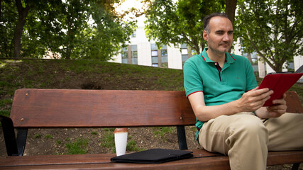 Fototapeta premium Man sitting outdoors with tablet