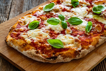 Pinsa Margherita with tomato sauce, basil leaves and mozzarella cheese on wooden background