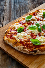 Pinsa Margherita with tomato sauce, basil leaves and mozzarella cheese on wooden background