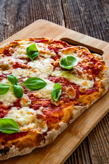 Pinsa Margherita with tomato sauce, basil leaves and mozzarella cheese on wooden background