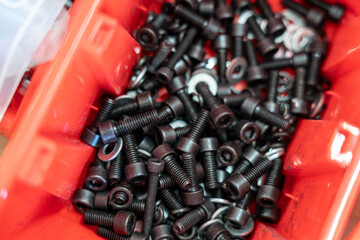 Close-up of Black Hex Screws and Washers in Red Storage Box