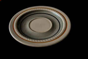 A decorative tray or coaster for a coffee or tea cup but it doesn't have to be just for that on a black background