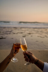 two couples holding drinking glasses and toasting with a beach sky in the background
