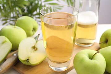 Fresh cider in glass, bottle, apples and knife on table, closeup