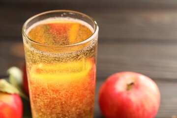 Delicious cider in glass and apples on table, closeup