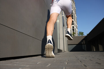 Man in sportswear running near building outdoors, closeup