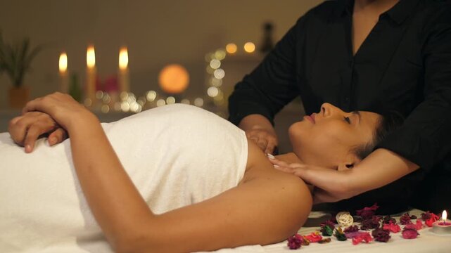 A relaxed woman gets her shoulder massage in a luxury spa by a professional massage therapist - wellness  healing  relaxation concept. Women lying on a massage table and relaxing while having a mas...