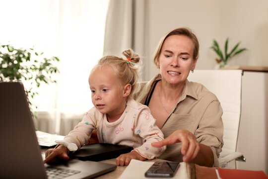 Mother and daughter interacting with a laptop in a home office