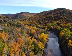 Autumnal river valley, vibrant fall foliage, rocky terrain, clear blue sky