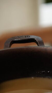 A black pot with the number 10 on it. The pot is sitting on a table. The pot is old and has a rustic look to it